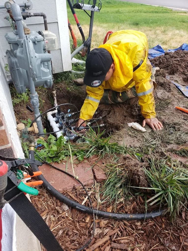 Person in yellow jacket examining the ground near gas meter and tools